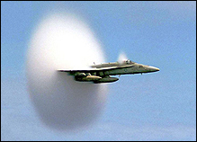 A jet plane flies faster than the speed of sound, creating a sonic boom.