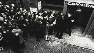 The Cavern Club is beseiged by a crowd of fans in the early days of Beatlemania in the UK.