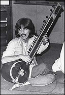 George Harrison plays a sitar on one of his trips to India.