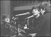 The Beatles performing on BBC radio in 1964. Left to right: John Lennon, Paul McCartney and George Harrison. Note that Lennon is wearing his dark-rimmed glasses; he wore them quite often to the radio performances if there wasn't a live audience for the show.