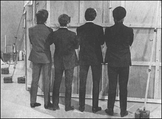 The Beatles pose facing the back of one of the set on their first feature film, A Hard Day's Night.